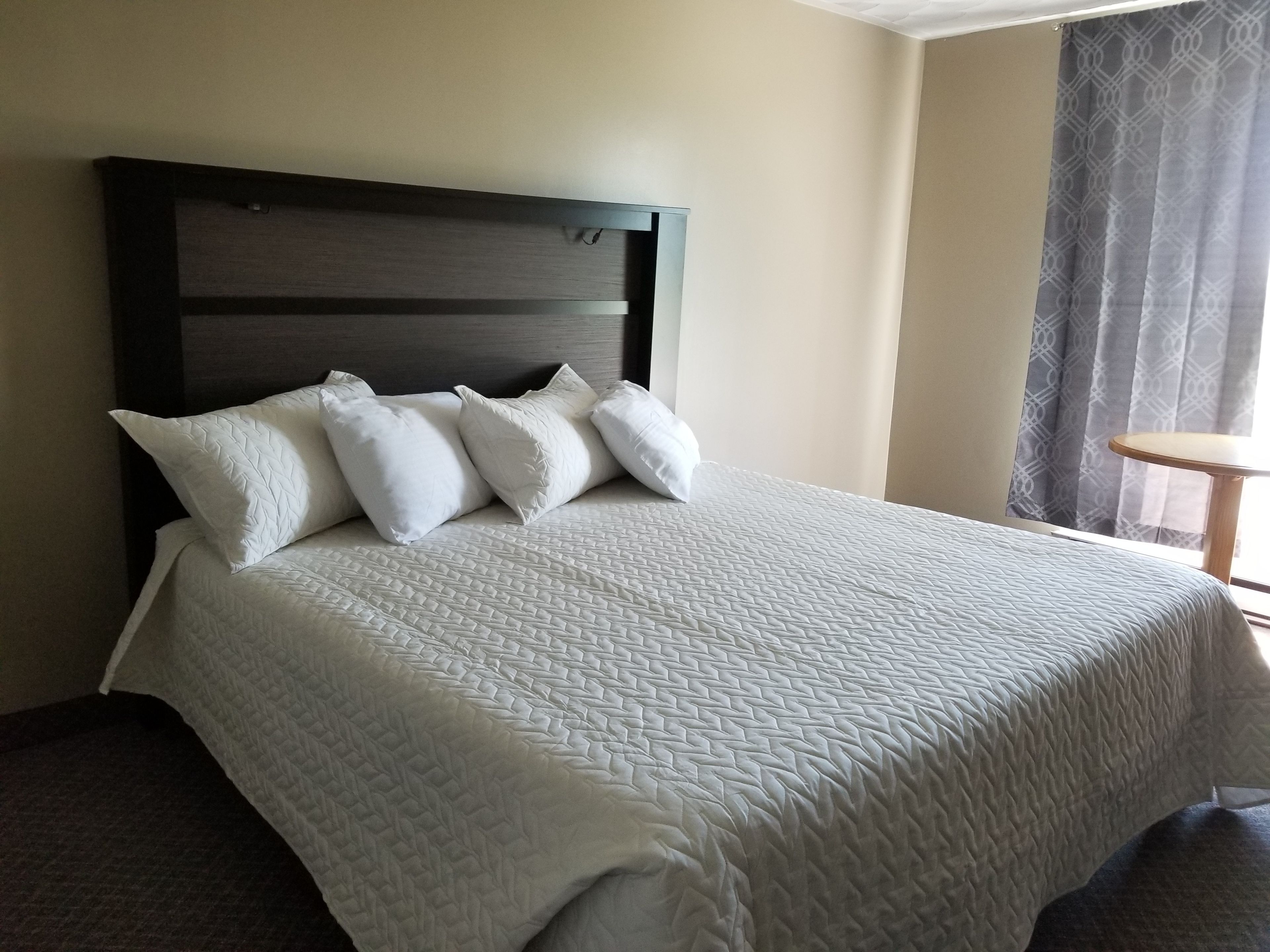 Una habitación de hotel con una cama grande, un cabecero de madera y una pequeña mesa redonda.