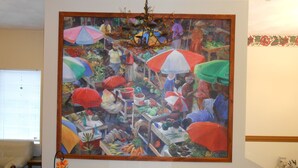 A large painting of a market scene with colorful umbrellas and various fruits and vegetables. - Knights Inn Woodstock (Jacksonville)