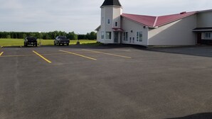 A building with a red roof and a white tower. There are two parked vehicles in a parking lot. - Knights Inn Woodstock (Jacksonville)