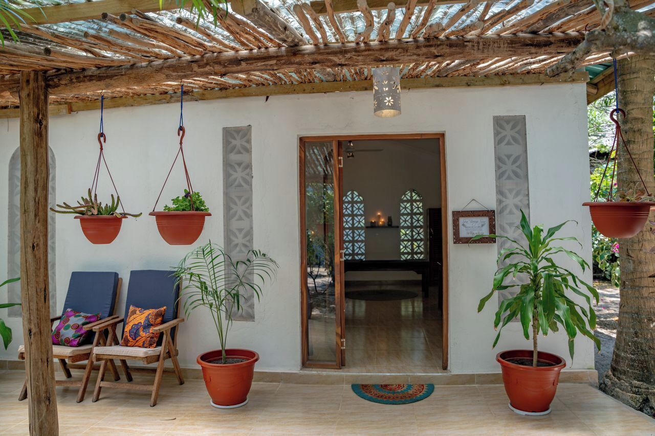 Un espacio al aire libre cubierto con sillas de madera y plantas en macetas.