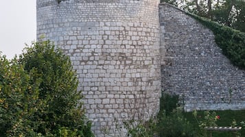 A stone tower with arched windows, surrounded by a well-maintained garden with shrubs and a lawn.