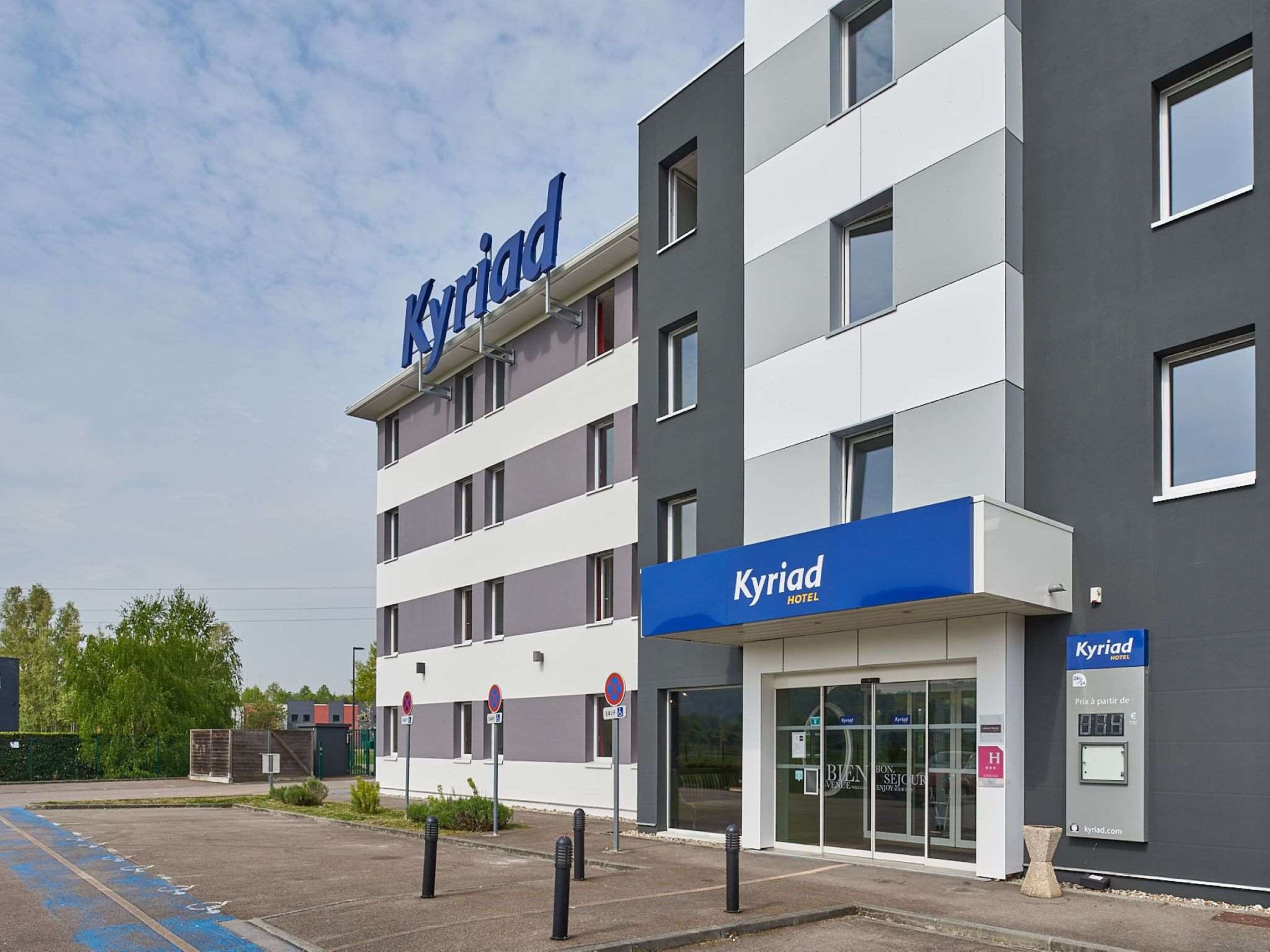 A modern hotel building with a prominent 'Kyriad' sign.