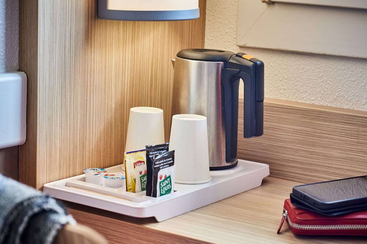 A coffee station with a coffee maker, cups, and coffee pods on a tray.