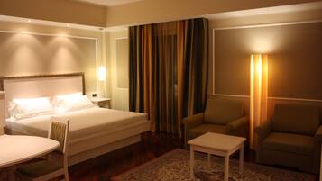 Ein Hotelzimmer mit Bett, zwei Sessel, einem kleinen Tisch und einem Nachttisch.