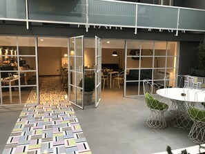 A modern interior with a patterned floor, a dining area with wire chairs, and a glass partition separating spaces. - Albergo del Pino (Cercola)