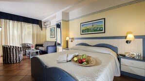 A hotel room with a bed, a chair, a small table, a lamp, and a painting on the wall. - Albergo del Pino (Cercola)