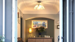 A cozy entrance with a black leather sofa, a small table with a lamp, a welcome sign, and a painting on the wall. - Albergo del Pino (Cercola)