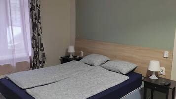 Une chambre à coucher avec un lit, deux tables de chevet, une commode et une fenêtre avec des rideaux.