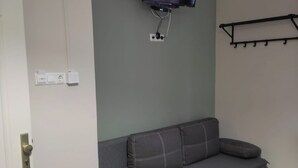 A modern living room with a grey sectional sofa, a mounted flat-screen TV, and a black wall-mounted shelf. - Downtown Apartments (Budapest)