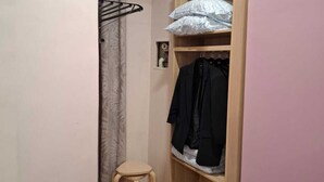 A small, narrow room with a wooden wardrobe, a stool, and a bed. - Downtown Apartments (Budapest)