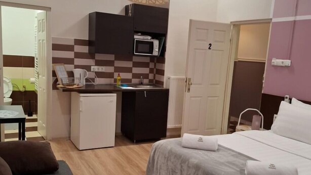 A compact bedroom with a bed, a small kitchenette, and a bathroom. - Downtown Apartments (Budapest)