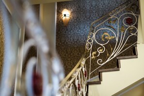 A staircase with ornate metal railings and a patterned wall. - Anagennisis Hotel (Pyrgos)