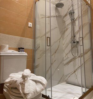 A glass-enclosed shower with a handheld showerhead and a wall-mounted faucet. - Anagennisis Hotel (Pyrgos)