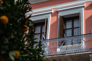 Un edificio con balcón, adornado con barandas de metal ornamentadas y una ventana con contraventanas.