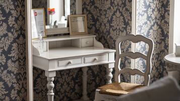 A white vanity with a mirror, a framed certificate, and a small bottle of hand sanitizer.
