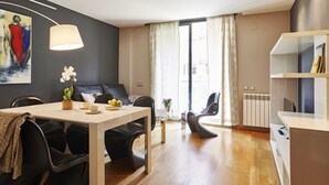 Una sala de estar moderna con comedor, un sofá, una mesa de centro y un cuadro en la pared.