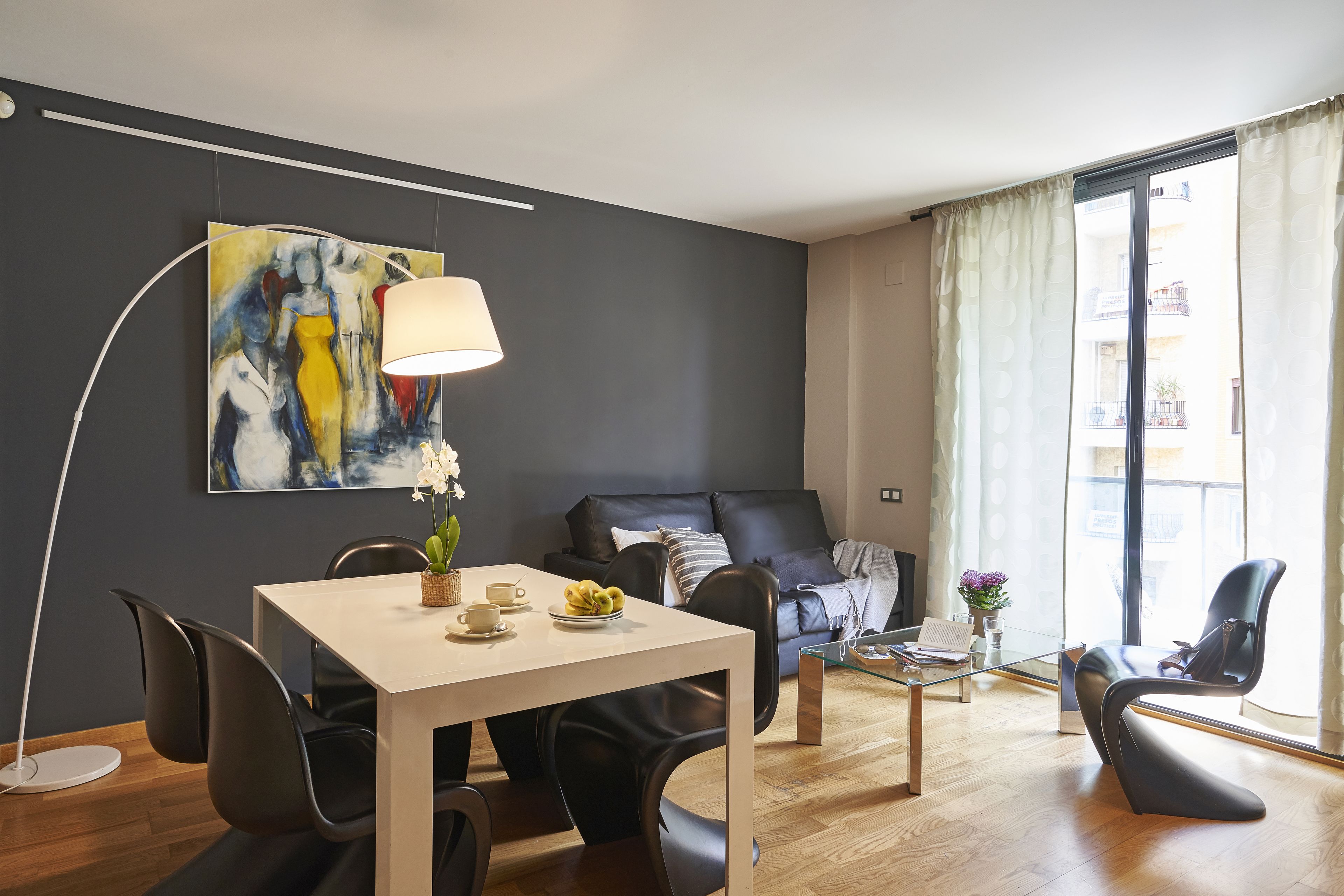 A modern living room with a sofa, a dining table with chairs, a coffee table, and a floor lamp.