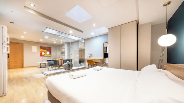 Una habitación de hotel moderna con una cama grande, un escritorio y un área de estar con sillas.