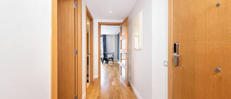 A hallway with wooden doors, a dining area in the background, and a ceiling light.