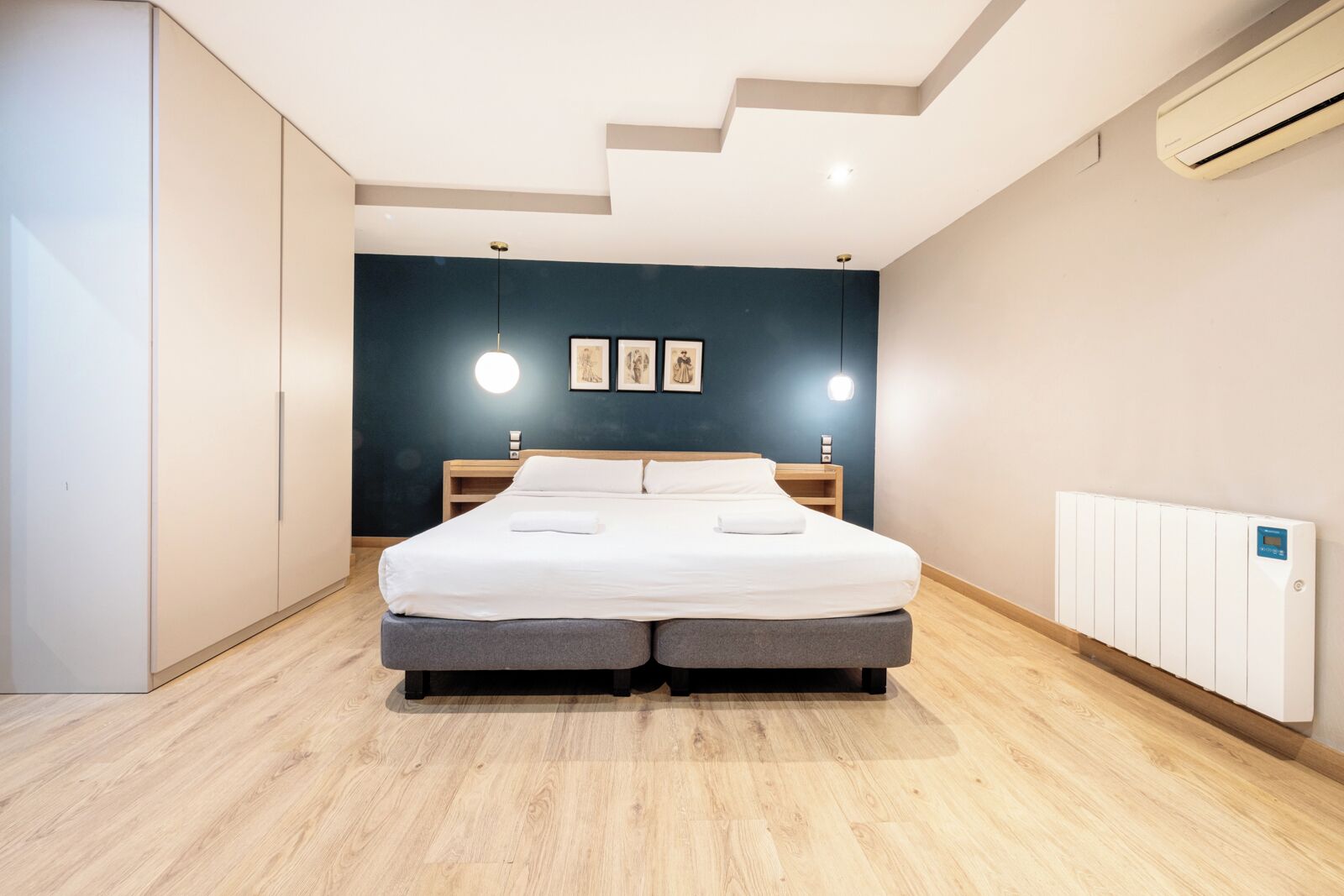 Een moderne slaapkamer met een groot bed, nachtkastjes, een kledingkast en een radiator.