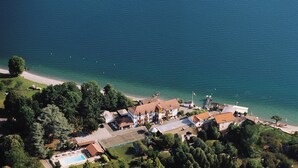 Vista aérea de uma propriedade costeira com vários edifícios, piscina e praia.