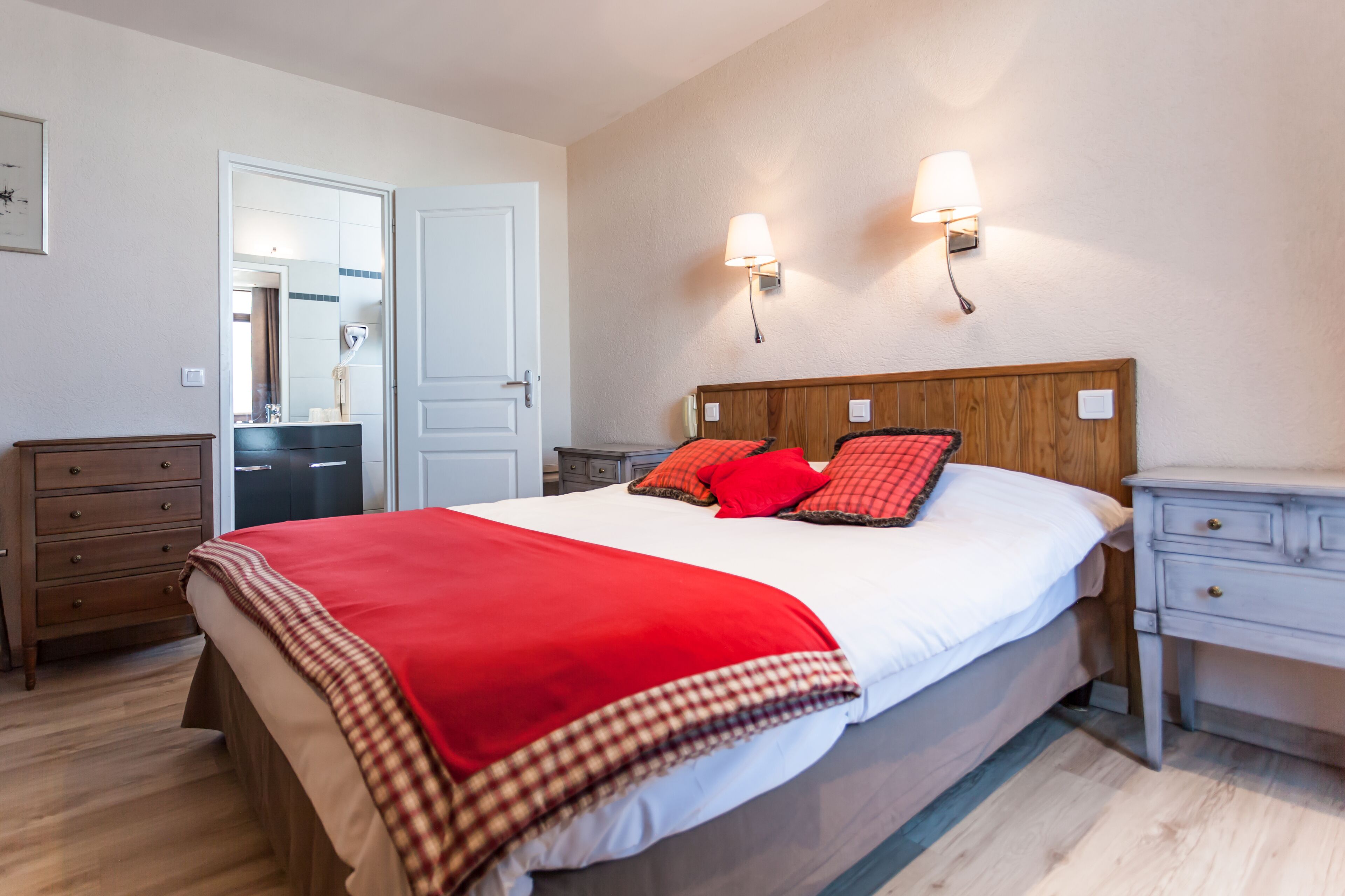 A bedroom with a large bed, two bedside tables, a dresser, and a mirror.