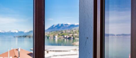 A view through a window of a building with a mountain in the background and a body of water in the foreground.