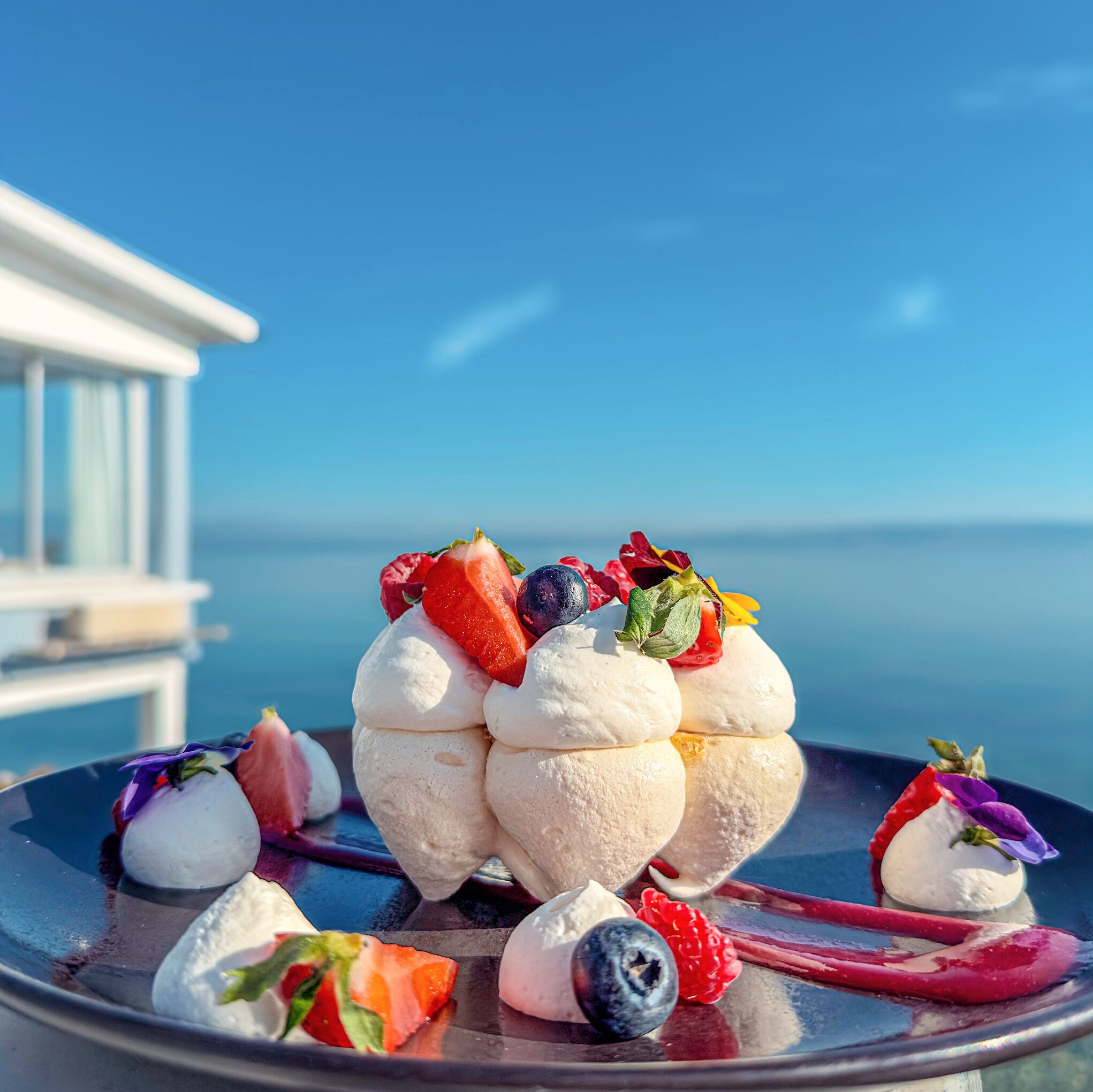 A dessert tray with ice cream and fresh fruits on a balcony with a clear view of the sea.