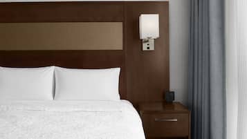 A hotel room with a large bed, a bedside table with a lamp, and a power outlet.