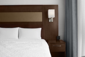 A hotel room with a large bed, a bedside table with a lamp, and a power outlet.