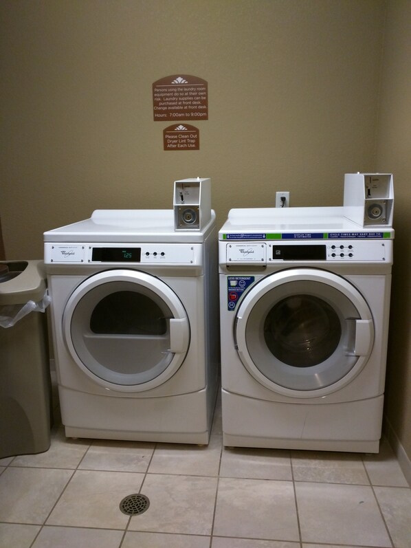 Two front-loading Whirlpool washers in a laundry room with a sign above them.