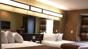 Habitación de hotel con dos camas, un televisor de pantalla plana, un escritorio y un espejo grande.