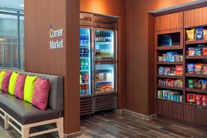 A corner market with refrigerated shelves stocked with beverages and snacks, a bench with colorful cushions, and wooden paneling. - Fairfield Inn & Suites Chicago Downtown/River North (Chicago)