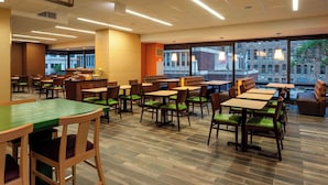 A restaurant with multiple tables and chairs, large windows, and a view of buildings outside. - Fairfield Inn & Suites Chicago Downtown/River North (Chicago)