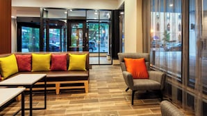 A lobby with a wooden floor, a sofa with colorful cushions, a chair with an orange cushion, and a glass door leading outside. - Fairfield Inn & Suites Chicago Downtown/River North (Chicago)
