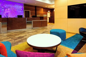 A hotel lobby with a reception desk, a television, a round table, and colorful seating. - Fairfield Inn & Suites Chicago Downtown/River North (Chicago)