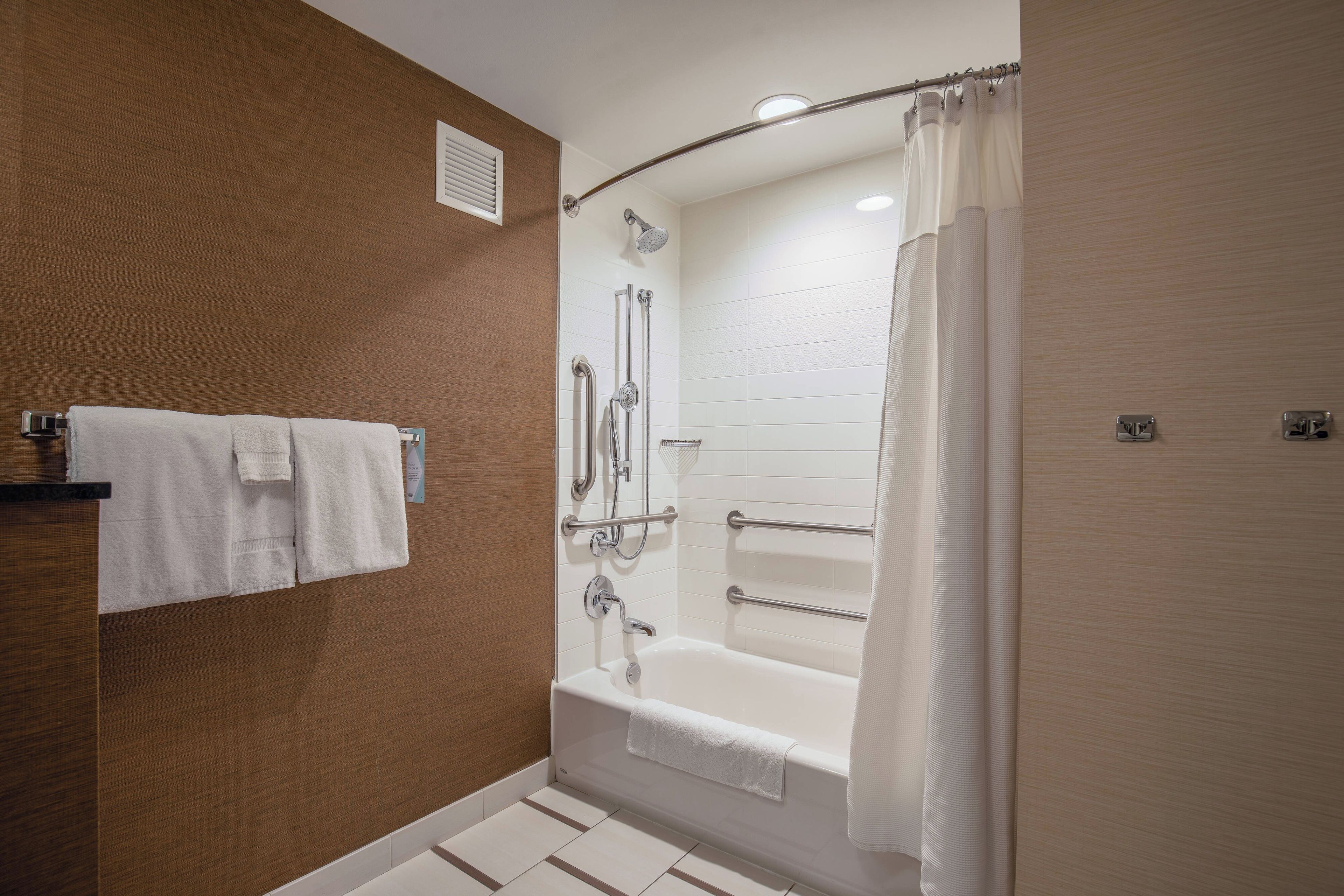 Un baño moderno con bañera, ducha y barras de apoyo.