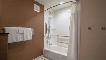 Un baño moderno con bañera, ducha y barras de apoyo.