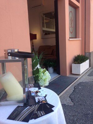Ein Empfangsbereich mit einem Tisch, auf dem Visitenkarten und Broschüren liegen, einer Zimmerpflanze und einer Tür zu einem Raum mit Balkon.