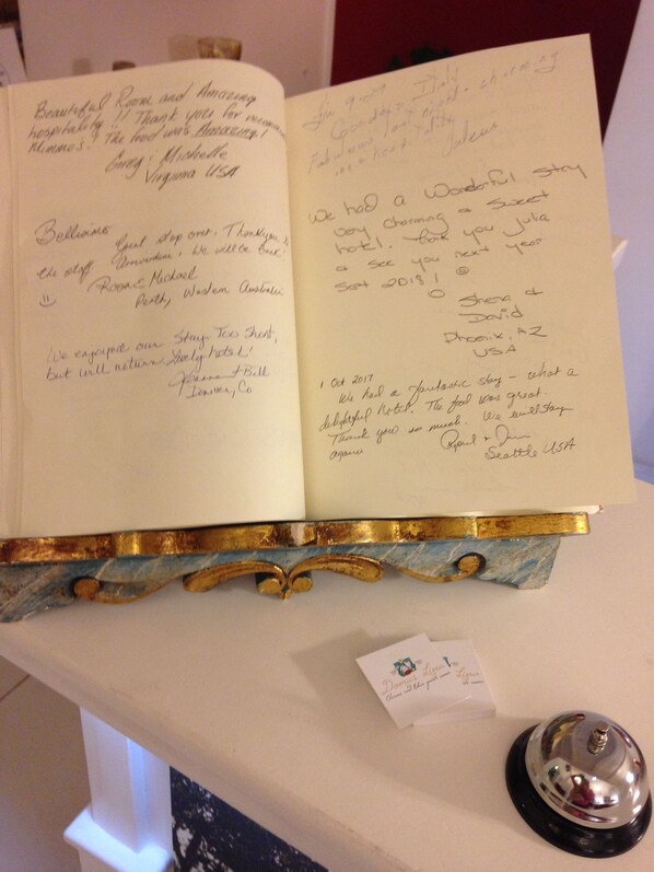 Un cuaderno abierto con notas escritas a mano, posiblemente un libro de visitas, sobre un soporte decorativo.