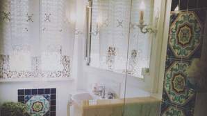 Un baño con lavamanos, espejo y azulejos estampados.