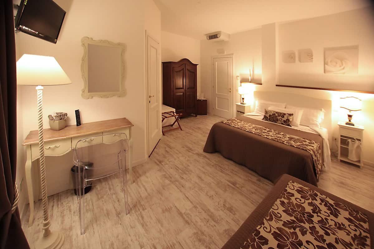 Ein Hotelzimmer mit zwei Betten, einem Schreibtisch, einem Stuhl, einem Fernseher und einem Kleiderschrank.
