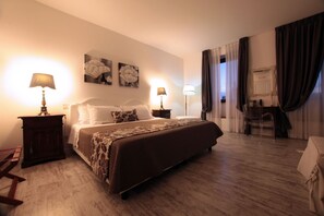 A hotel room with a large bed, two bedside tables with lamps, a desk with a chair, and a mirror. - Domus Lina (Fiumicino)