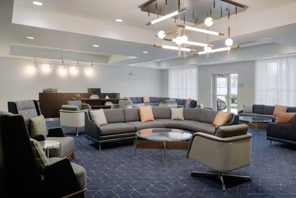 A modern lobby with a sectional sofa, armchairs, and a glass coffee table.