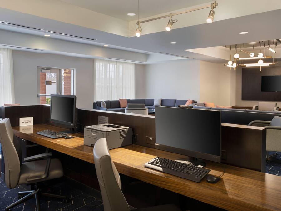 A modern office space with individual workstations, a large flat-screen TV, and a conference area with a sofa.