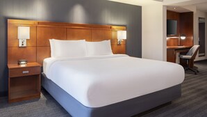 A hotel room with a large bed, bedside lamps, a desk with a chair, and a mirror. - Courtyard Columbus New Albany (New Albany)