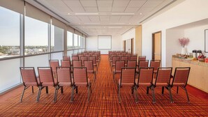 A conference room with rows of chairs, large windows, and a carpeted floor. - Courtyard by Marriott Leon at the Poliforum (León)