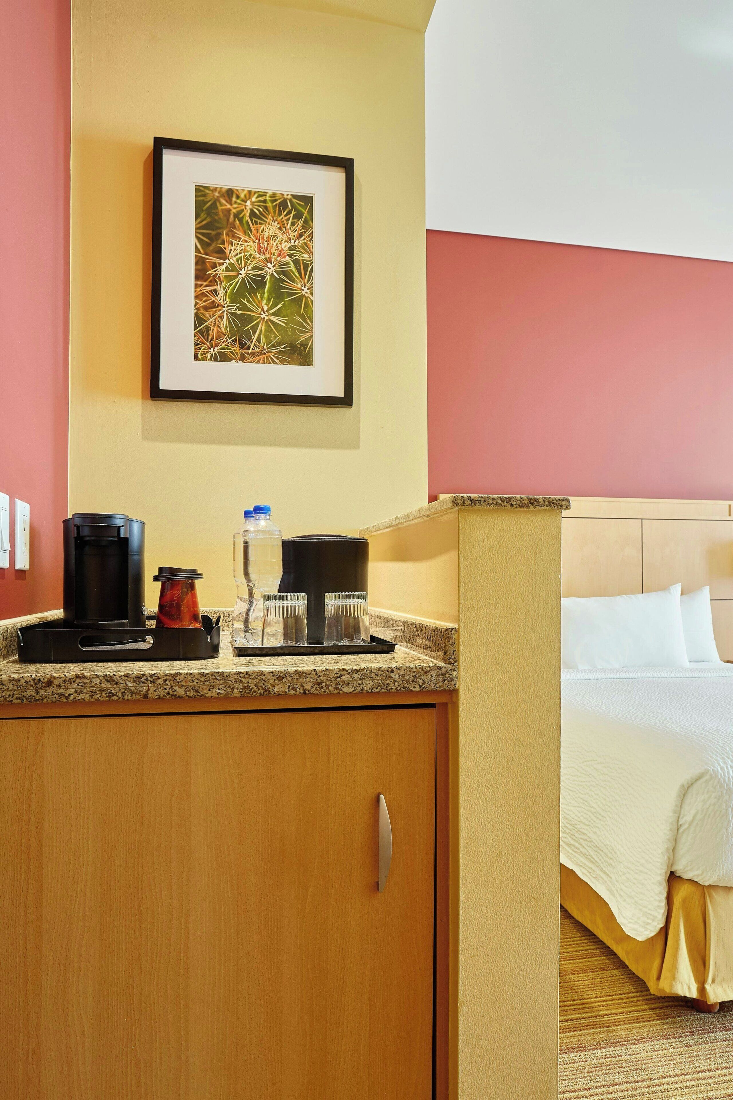 Una habitación de hotel con cama, estación de café y un cuadro en la pared.