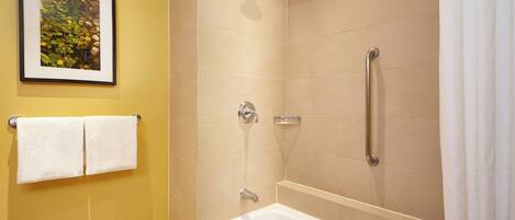 A bathroom with a bathtub, a shower, and a framed picture on the wall.