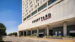 A Courtyard by Marriott hotel with a modern facade, large windows, and a prominent entrance. - Courtyard by Marriott Leon at the Poliforum (León)